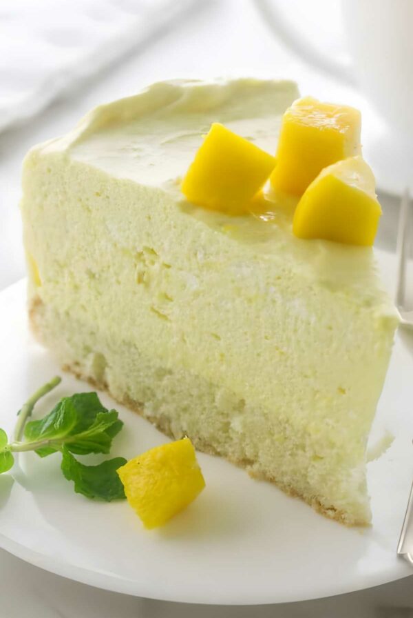 A slice of mango mousse cake on a white plate.