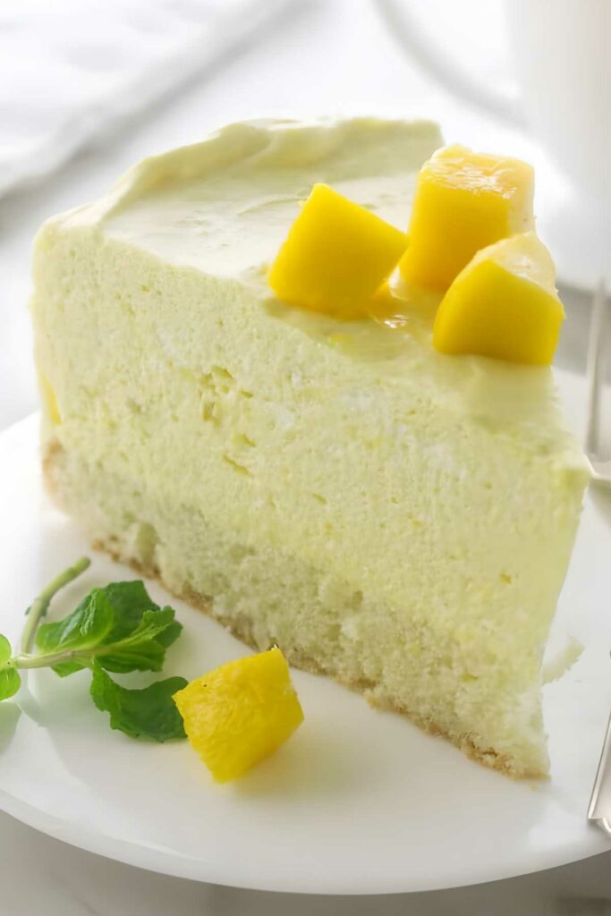 A slice of mango mousse cake on a white plate.