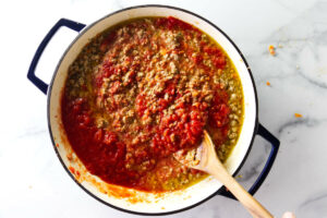 Stirring the bolognese sauce with a spoon.