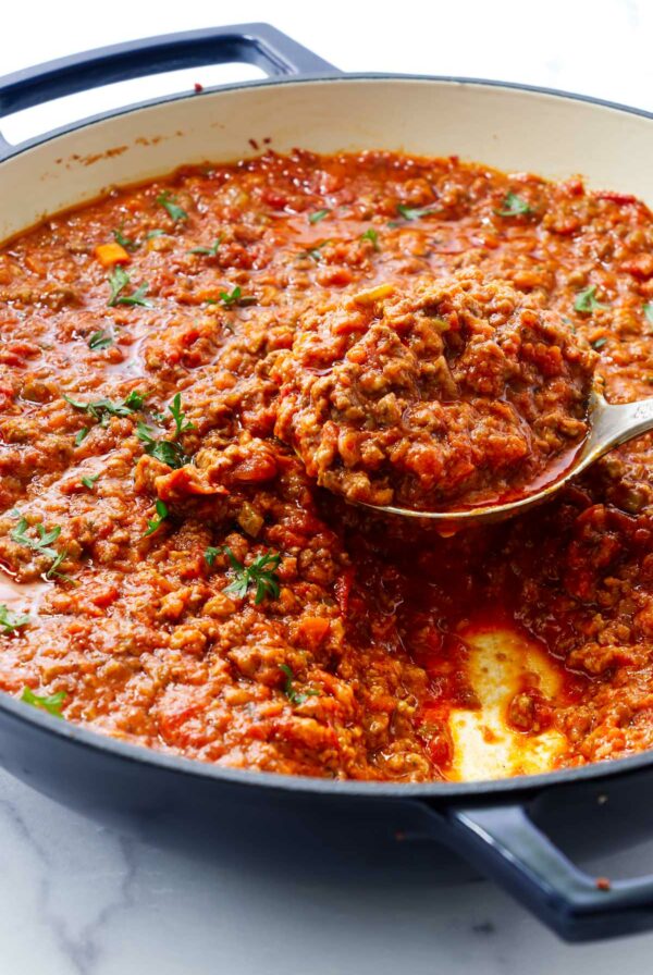Scooping a serving of pasta bolognese sauce.