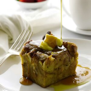 Bread pudding slice with butter and syrup, syrup being poured on top.
