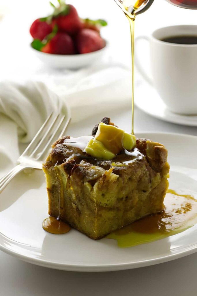 Apple French toast casserole slice with butter and syrup, syrup being poured on top.