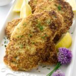 Breaded chicken cutlets with chives, lemon, chive flowers, and creamy sauce.