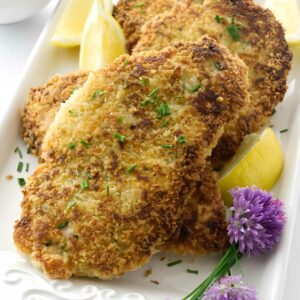 Breaded chicken cutlets with chives, lemon, chive flowers, and creamy sauce.