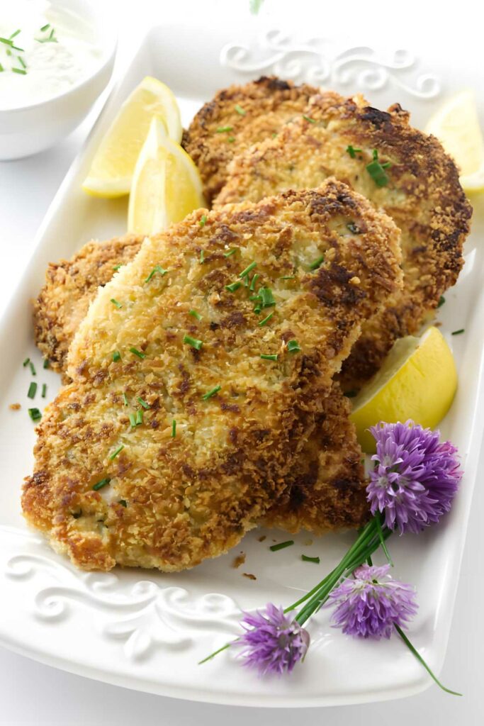 Breaded chicken cutlets with chives, lemon, chive flowers, and creamy sauce.