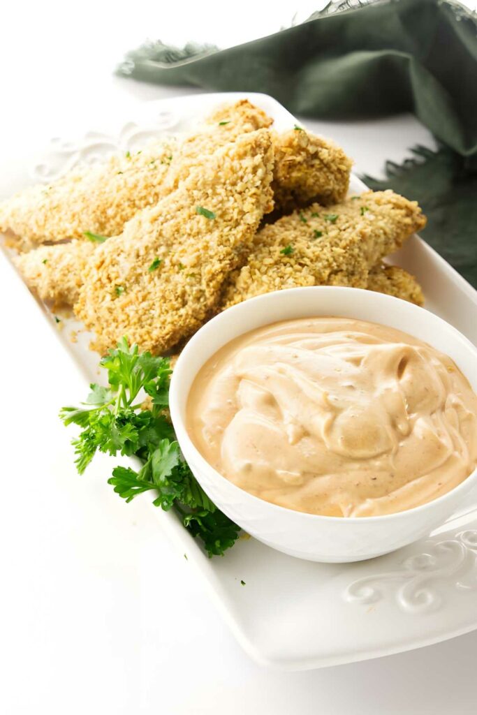 Crispy chicken tenders with parsley, creamy dipping sauce, and fresh parsley.