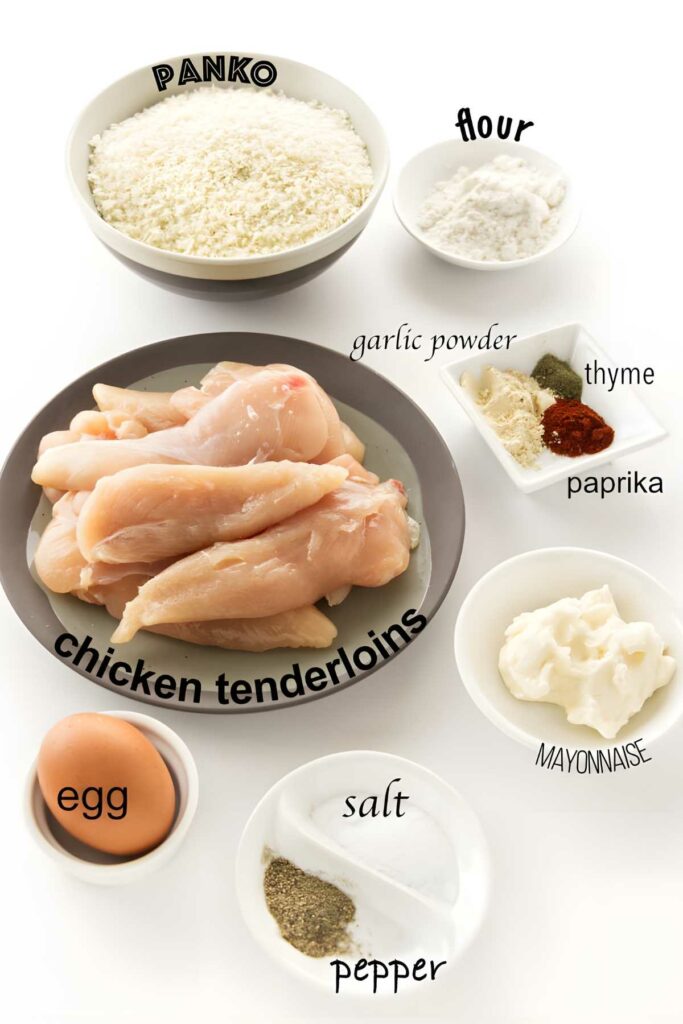 Chicken tenderloin recipe ingredients arranged on white surface, including spices and breadcrumbs.