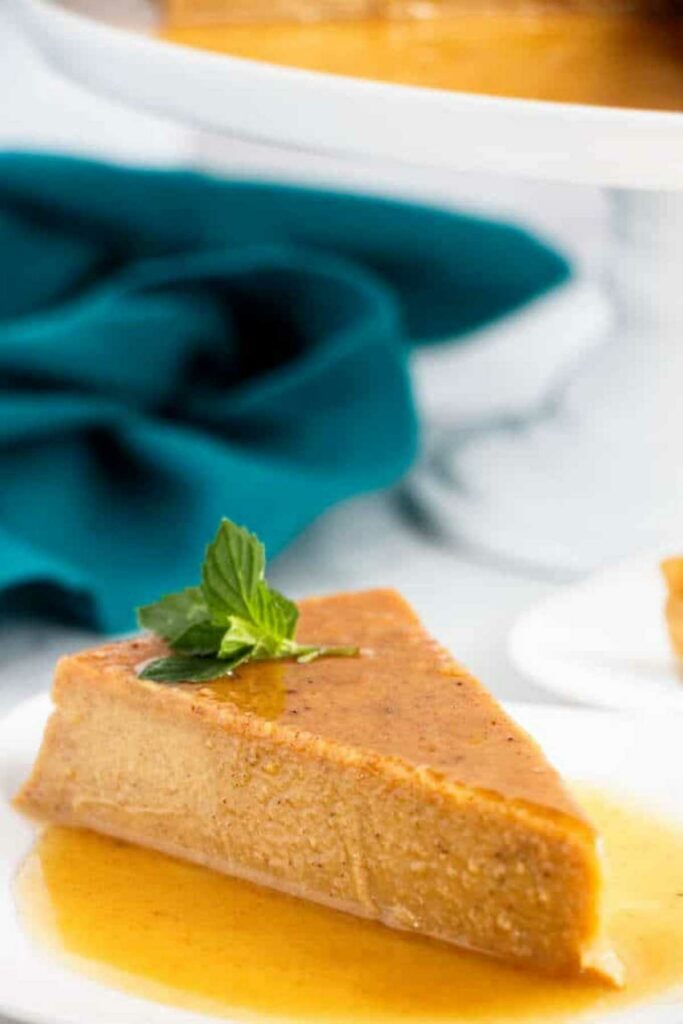 Pumpkin caramel flan slice with mint on white plate.
