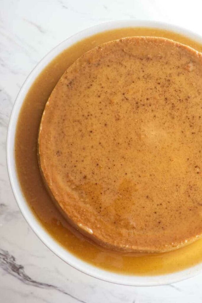 Close-up of flan topped with caramel sauce in a white dish.