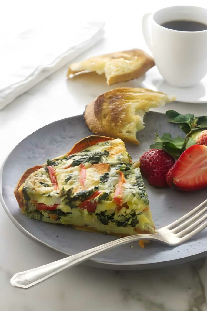 Vegetable quiche slice with spinach, sweet potato and a cup of coffee.