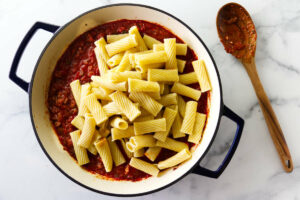 Adding rigatoni pasta to the sausage sauce.