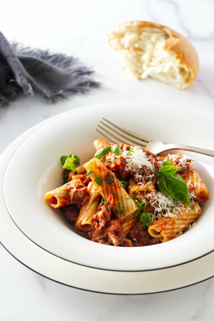 A pasta bowl filled with rigatoni and sausage sauce.