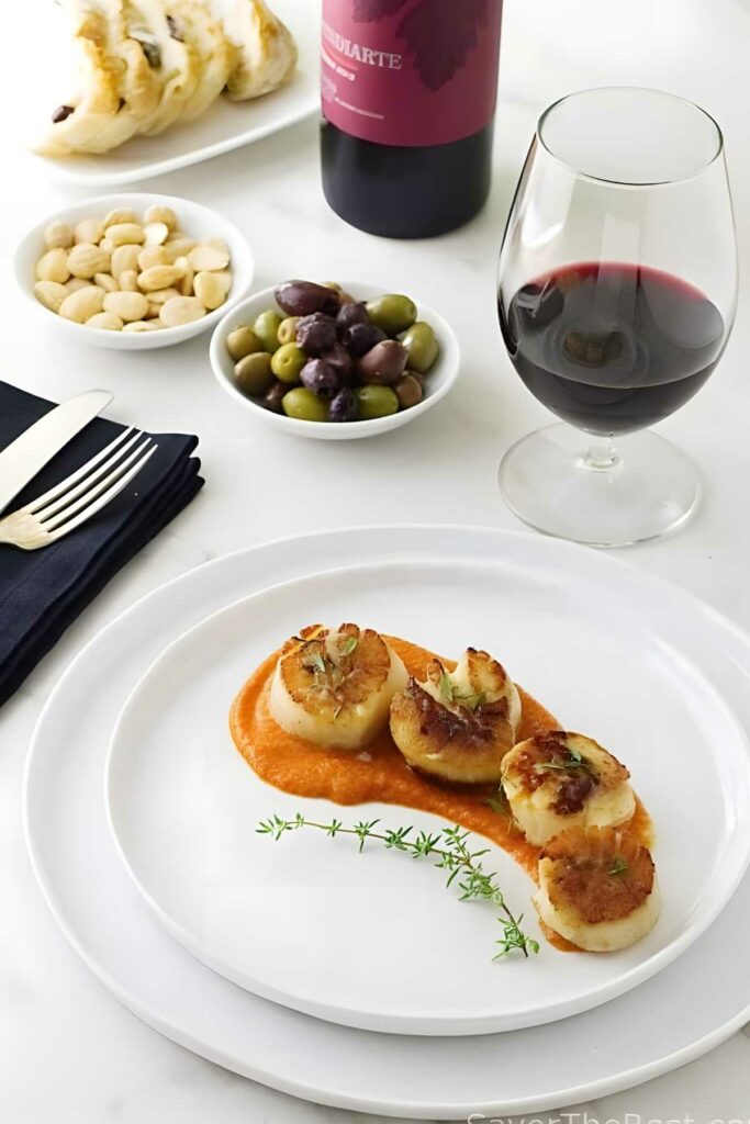 Seared scallops on romesco sauce with red wine, olives, bread, and almonds.