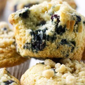 Close-up of blueberry muffins, one halved to show moist, juicy interior.