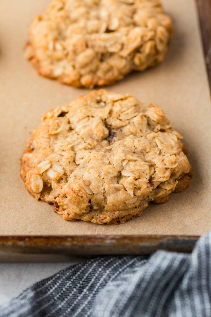 Two sourdough oatmeal cookies on parchment paper.