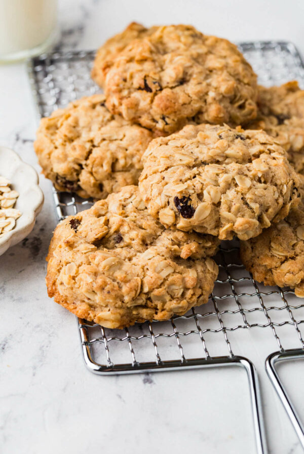 A pile of thick oatmeal raisin cookies on a rack.