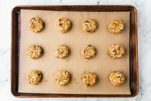 Adding sourdough oatmeal cookie dough to a sheet pan.
