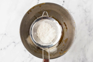 Sifting flour into the sourdough cookie dough.