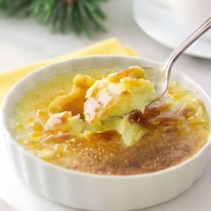 Spoon scooping custard from crème brûlée with caramelized sugar crust.