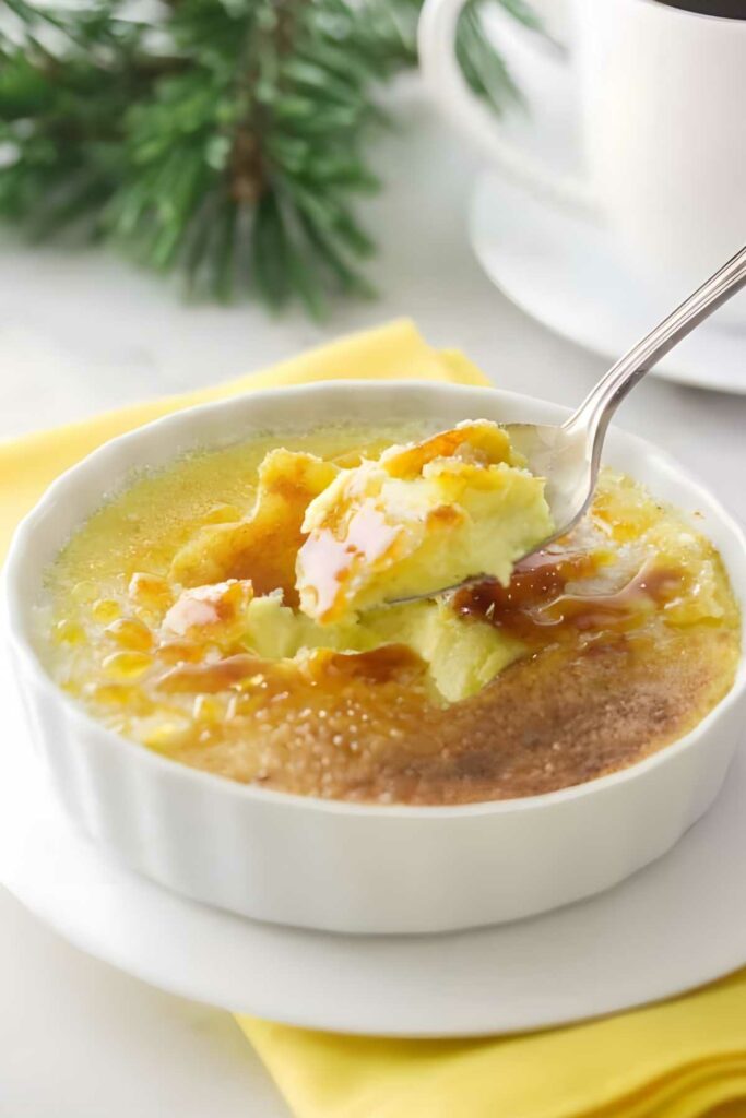 Spoon scooping custard from crème brûlée with caramelized sugar crust.