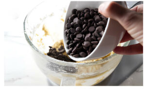 Adding chocolate chips to cookie dough.