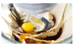 Adding eggs to cookie dough.