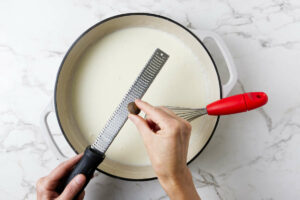 Grating nutmeg into the bechemel sauce.