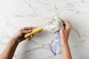 Piping a beef and cheese mixture into a cannelloni pasta tube.