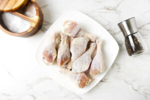 Adding salt and pepper to chicken legs.