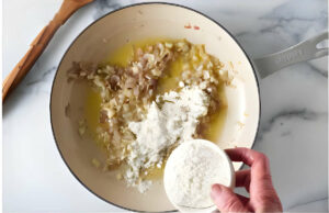 Adding flour to a skillet to make a bechemel white sauce.