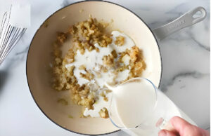 Adding milk to the skillet to make a white sauce.