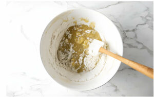 Folding the dry ingredients into the batter with a spatula.