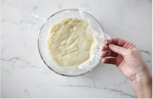 Covering the pastry cream with plastic wrap.