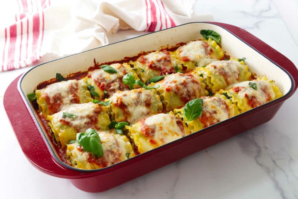 A baking dish filled with Lasagna spirals and a cloth in the background.