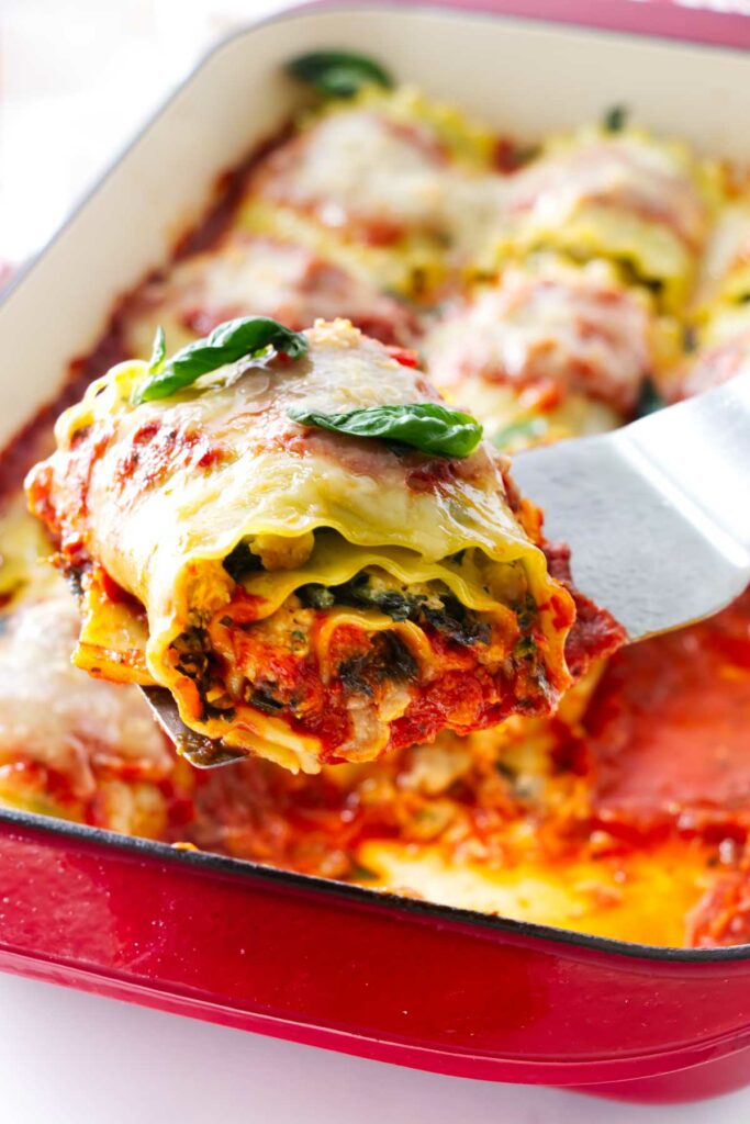 Stuffed lasagna noodles rolled into spirals being lifted with a spatula.