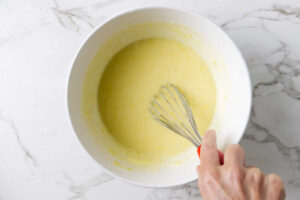 A whisk stirring the wet ingredients for a muffin recipe.