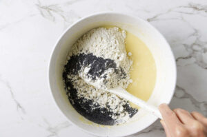 Folding the poppyseeds and dry ingredients into lemony muffin batter.