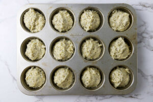 Dividing poppy seed muffin batter into muffin tin wells.