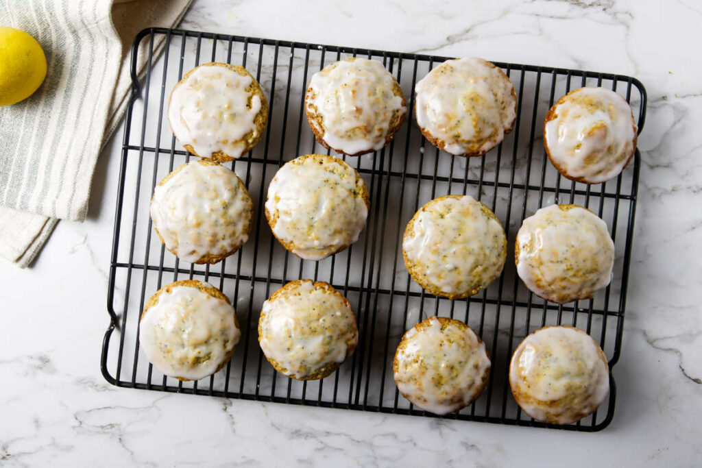 Twelve lemon poppy seed muffins cooling on a wire rack.