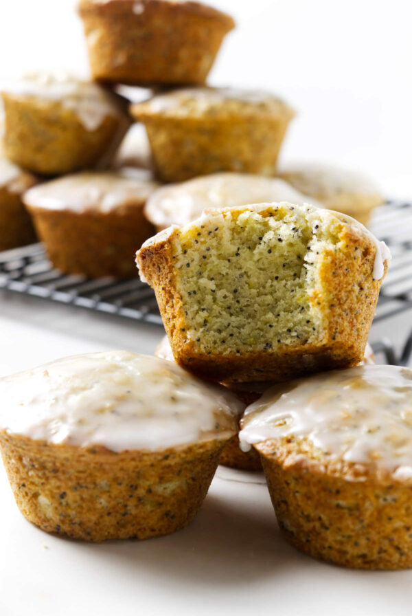 A stack of lemon poppy seed muffins with more muffins in the background.