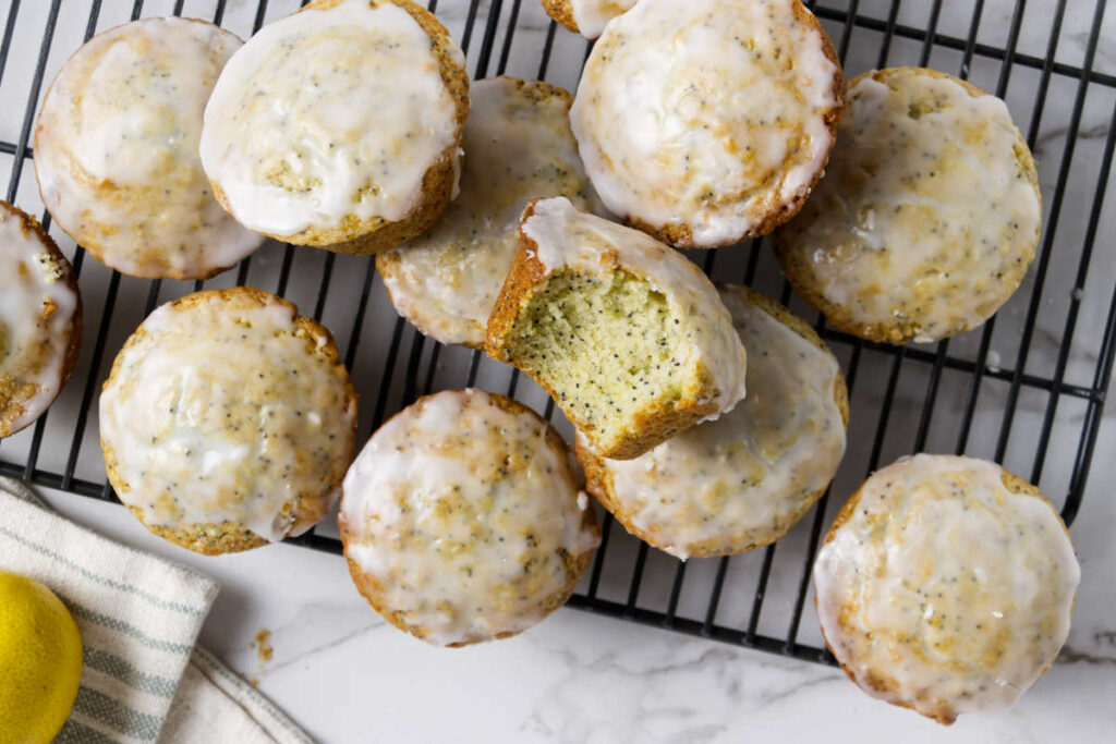 A batch of lemon poppy seed muffin recipe on a rack with lemon glaze.