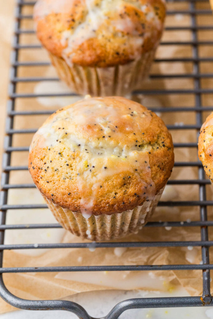 A sourdough poppy seed muffin on a cooling rack with glaze.