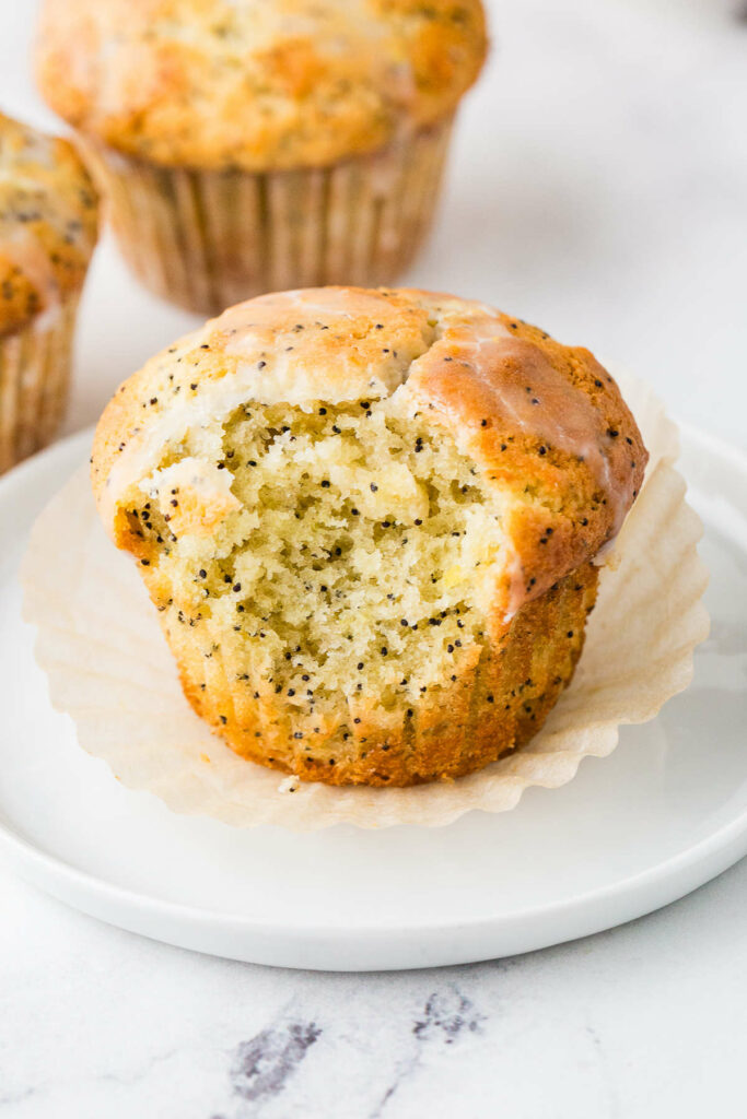 A partially eaten sourdough lemon muffin with poppy seeds.