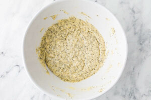 Combining the poppy seeds to the muffin batter in the bowl.