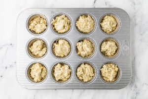 Portioning the batter into twelve muffin wells.