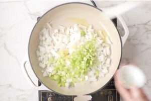 Cooking onions and celery in a skillet.