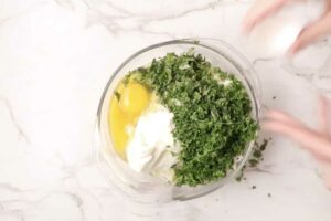 Mixing cottage cheese with egg and cheese and parsley.