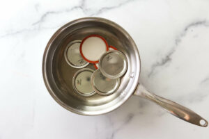Heating canning lids in a pan of hot water.
