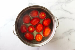 Blanching tomatoes in hot water in a large pot.