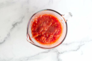 Measuring the cooked tomatoes in a measuring cup.